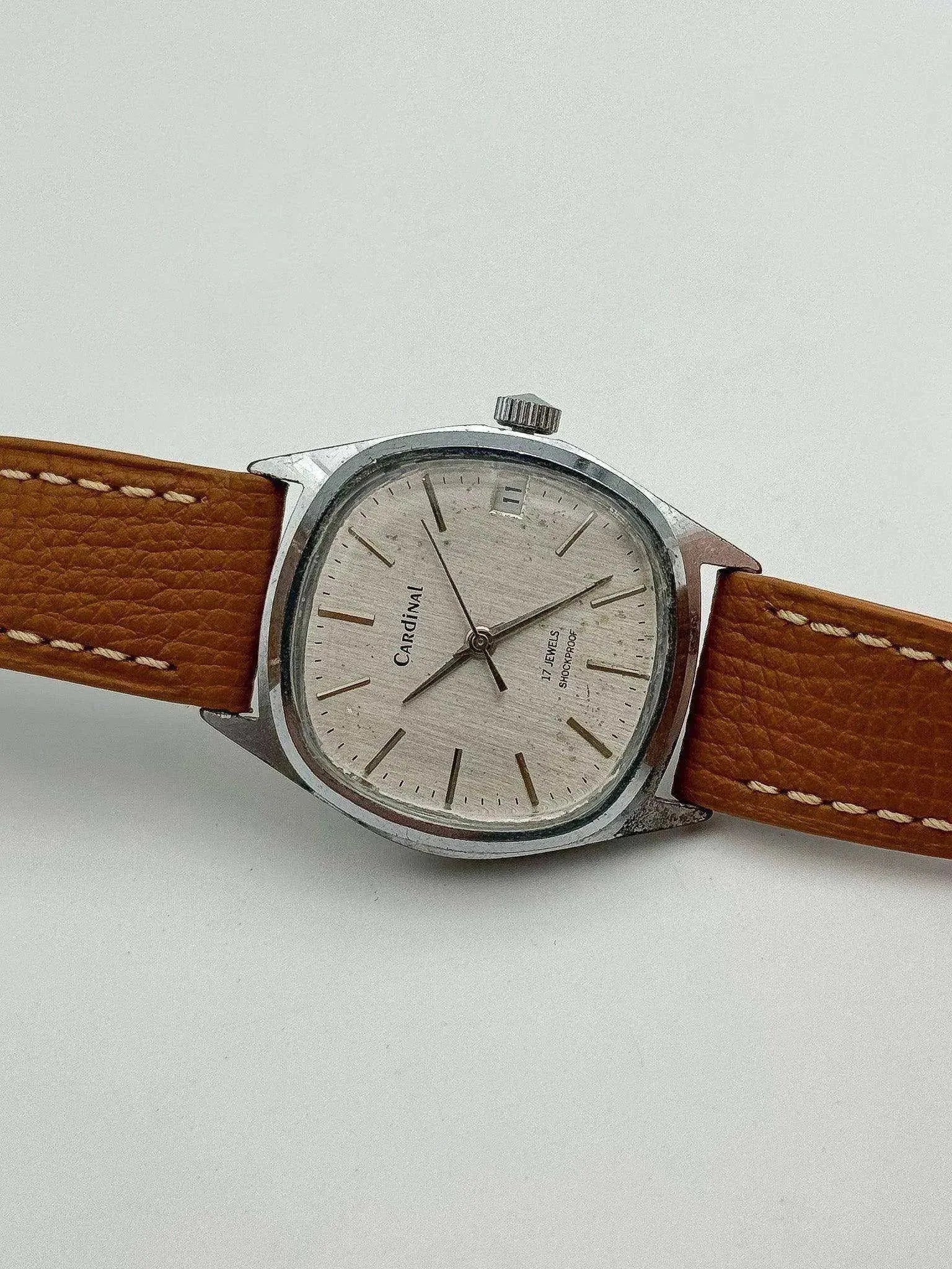 Vintage Cardinal watch with silver dial, brown leather strap, and steel case on white background