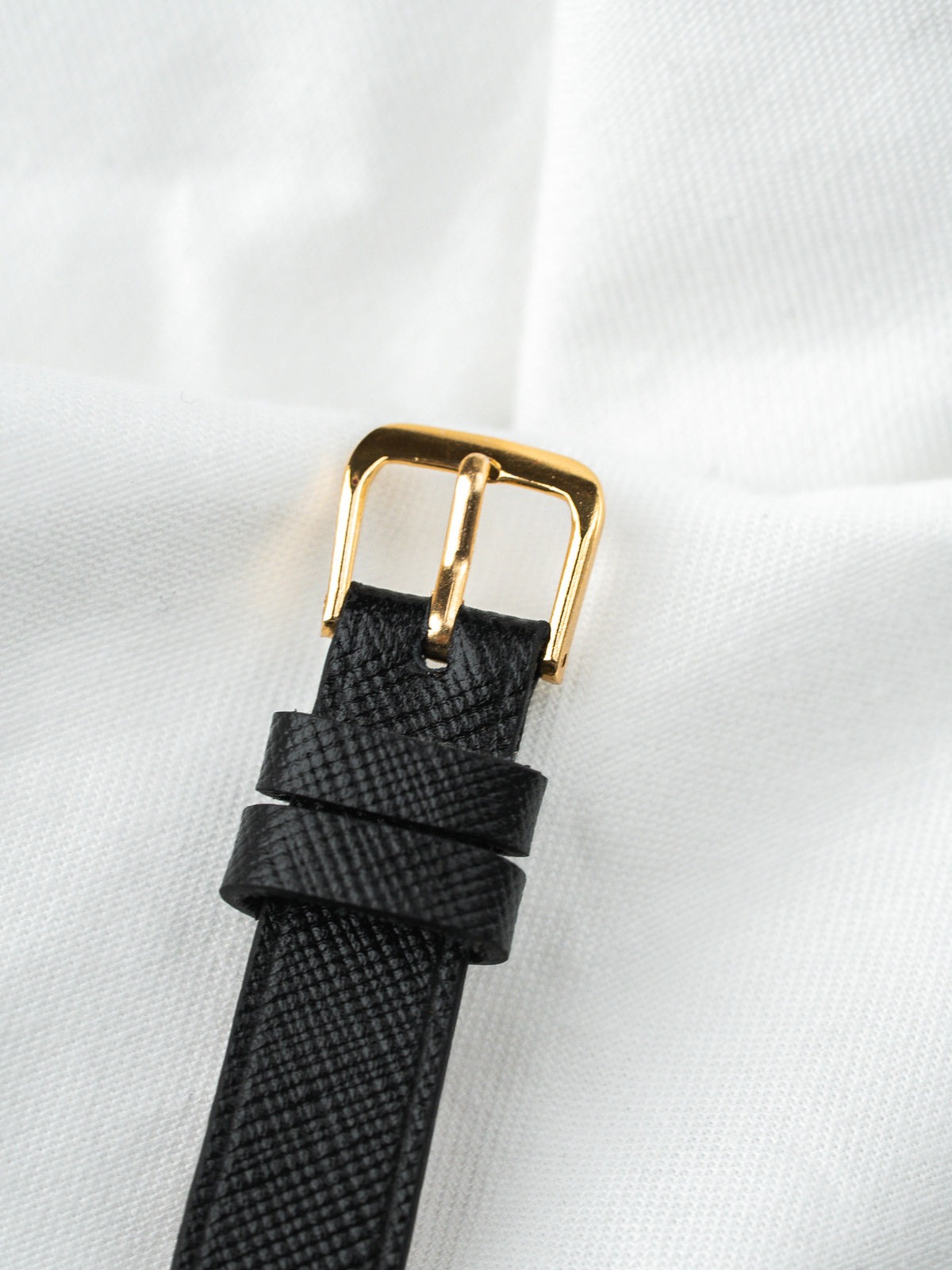 Boucle de bracelet de montre en or avec cuir noir grainé sur fond blanc