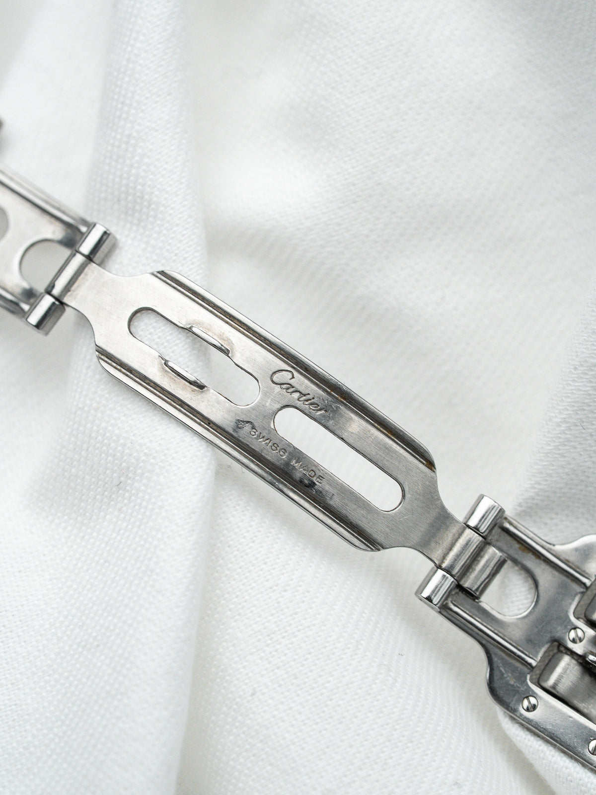 Fermoir de bracelet Cartier en acier inoxydable, gravure Swiss Made, sur fond blanc