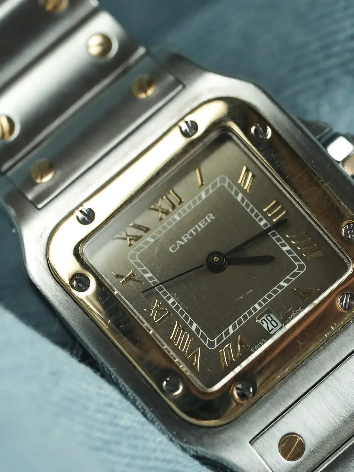 Cartier Santos vintage watch with square case, gold Roman numerals, and steel bracelet
