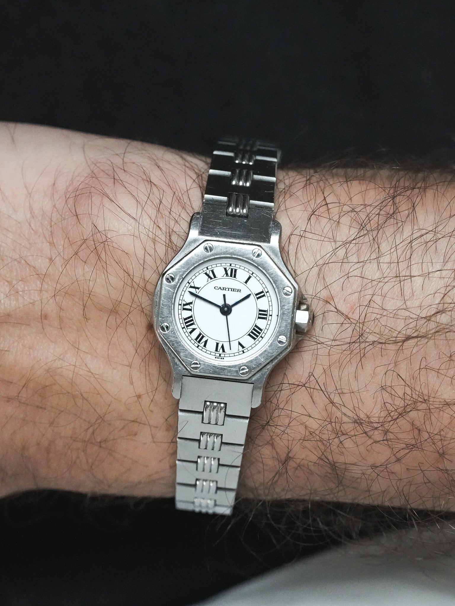 Cartier Santos watch with octagonal case, white dial, Roman numerals, steel bracelet on wrist