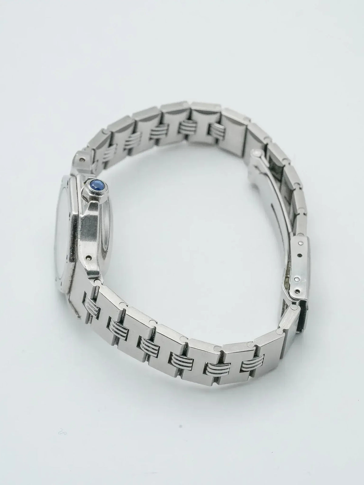 Vintage Cartier watch with steel bracelet and blue cabochon crown on white background