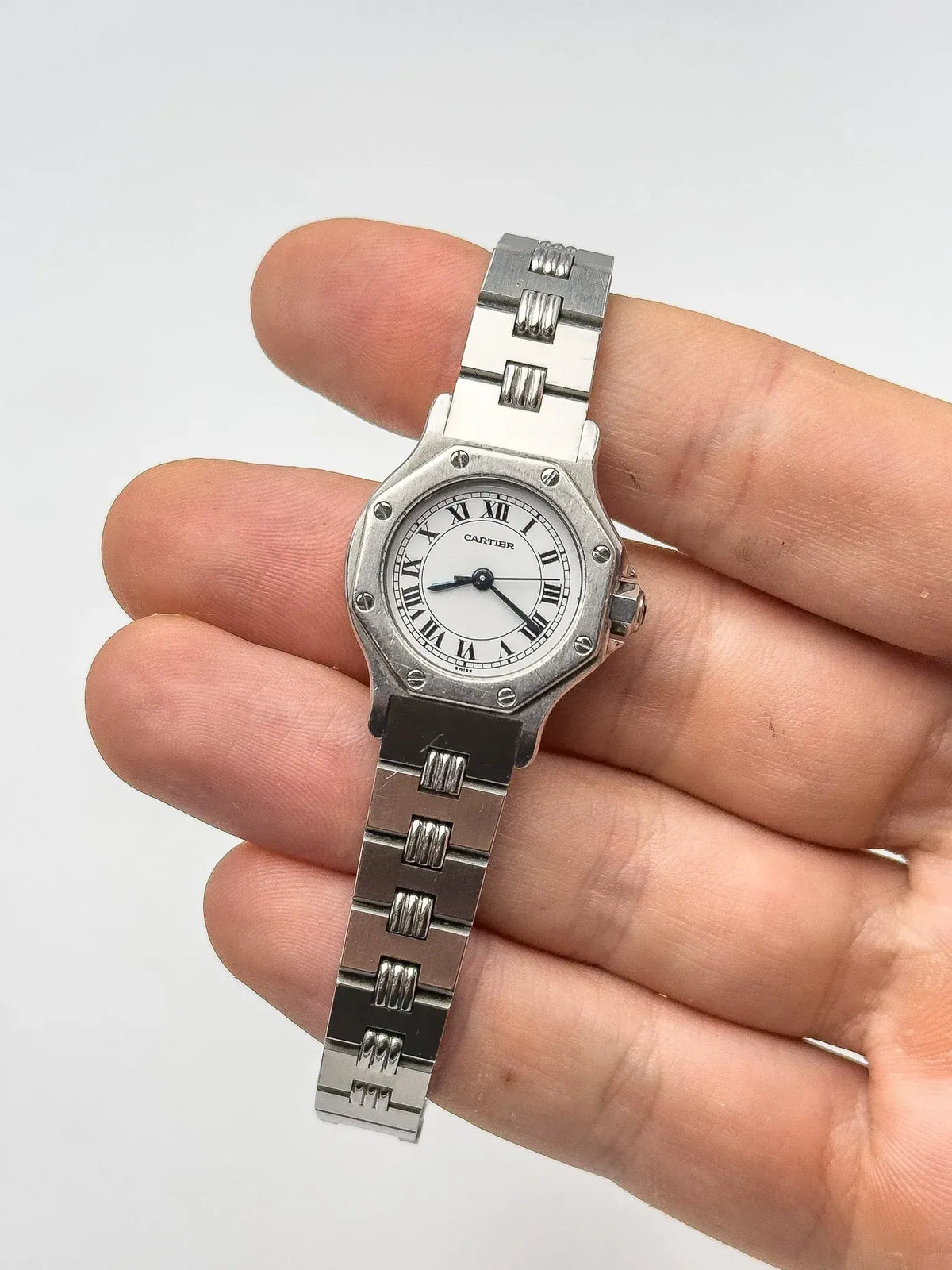 Cartier Santos watch with octagonal case, white dial, Roman numerals, steel bracelet held in hand