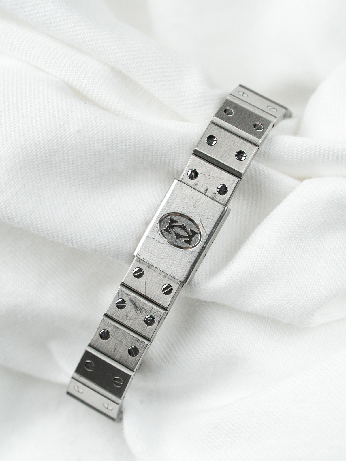 Bracelet de montre vintage en acier inoxydable avec logo central sur fond blanc