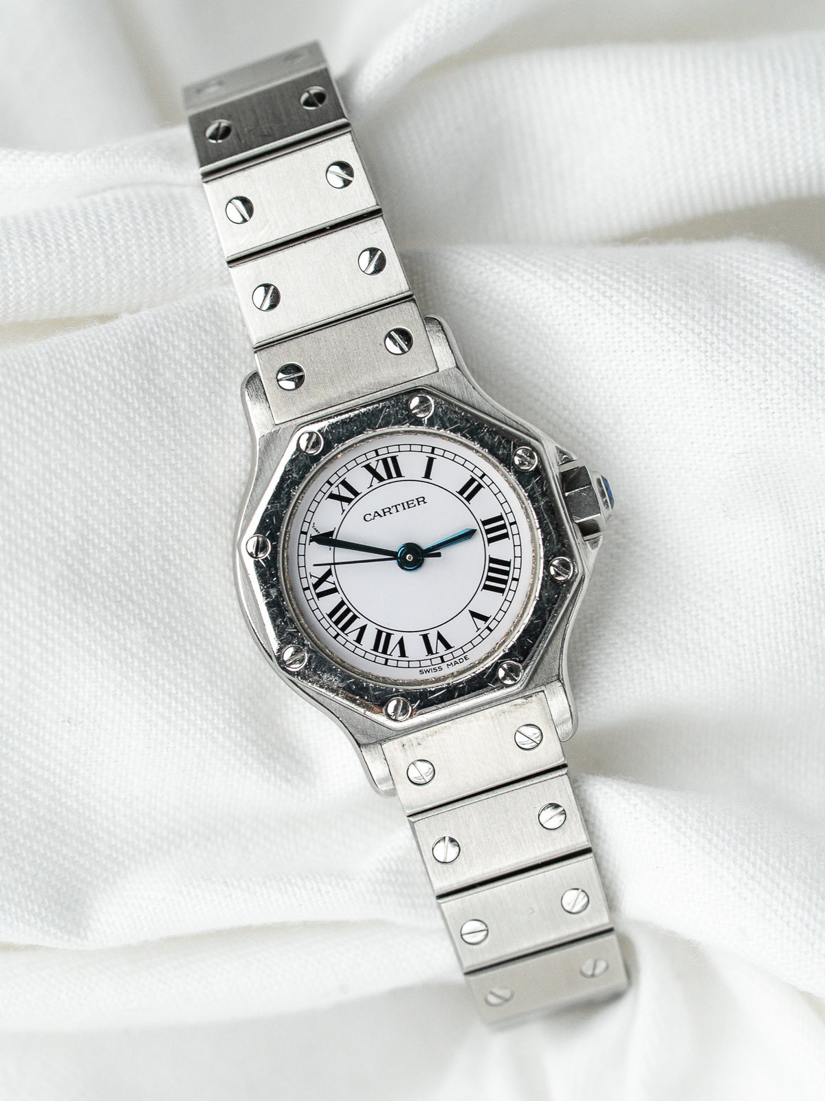 Montre Cartier vintage en acier, cadran blanc et bracelet métallique, sur fond blanc