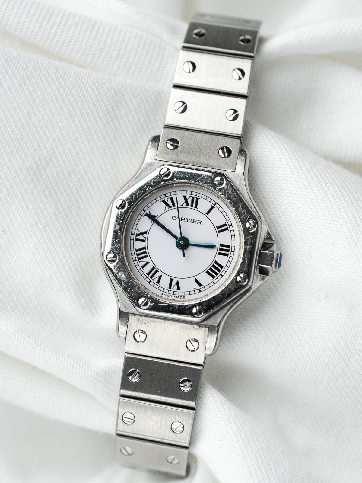 Montre Cartier vintage en acier, cadran blanc et bracelet métallique sur fond blanc