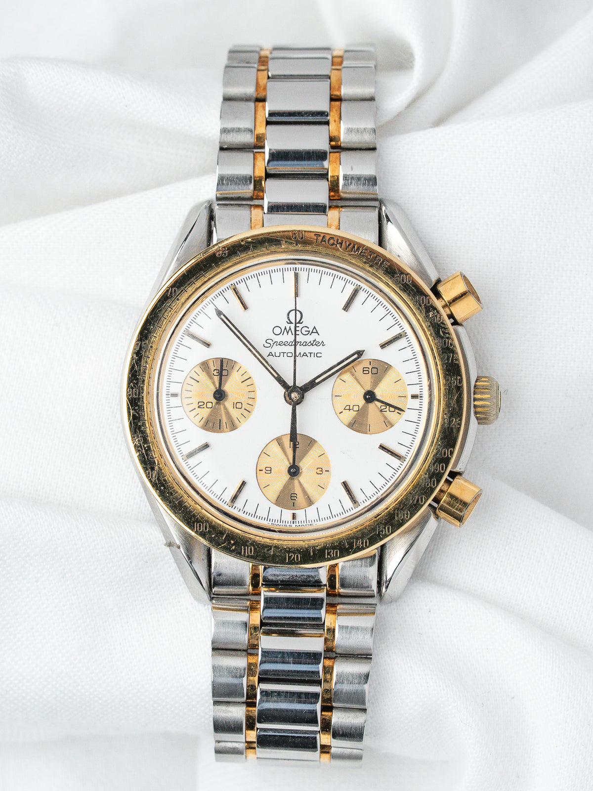 Omega Speedmaster vintage chronograph with white dial, gold subdials, and two-tone bracelet