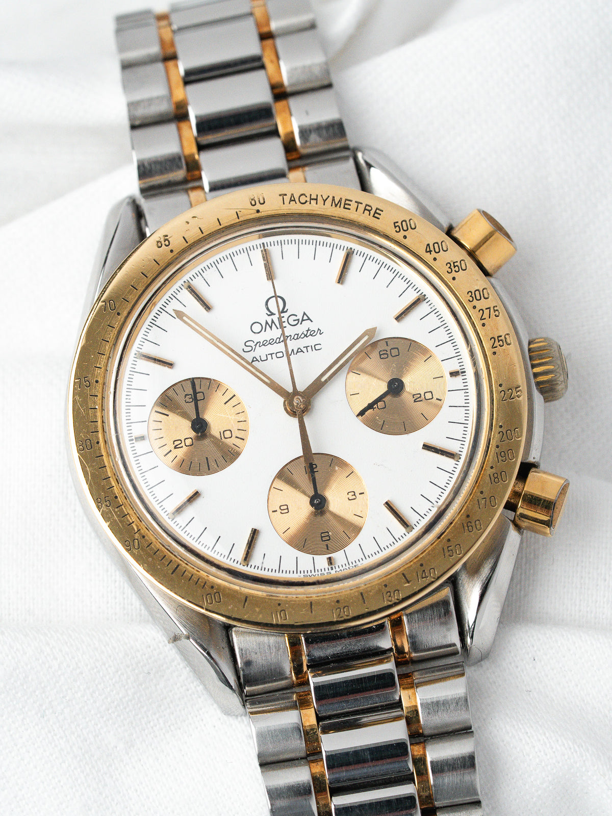 Omega Speedmaster vintage chronograph with white dial, gold subdials, and two-tone bracelet