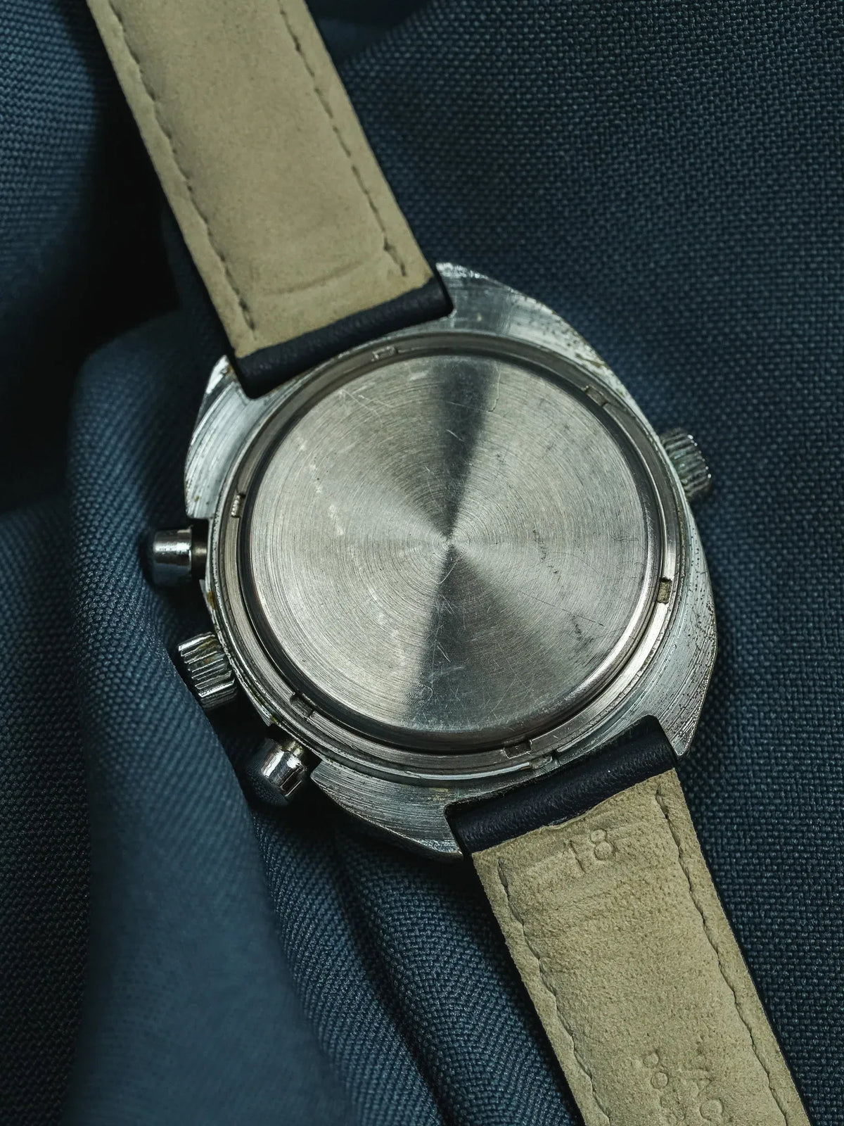 Vintage chronograph watch back with brushed steel case and beige leather strap