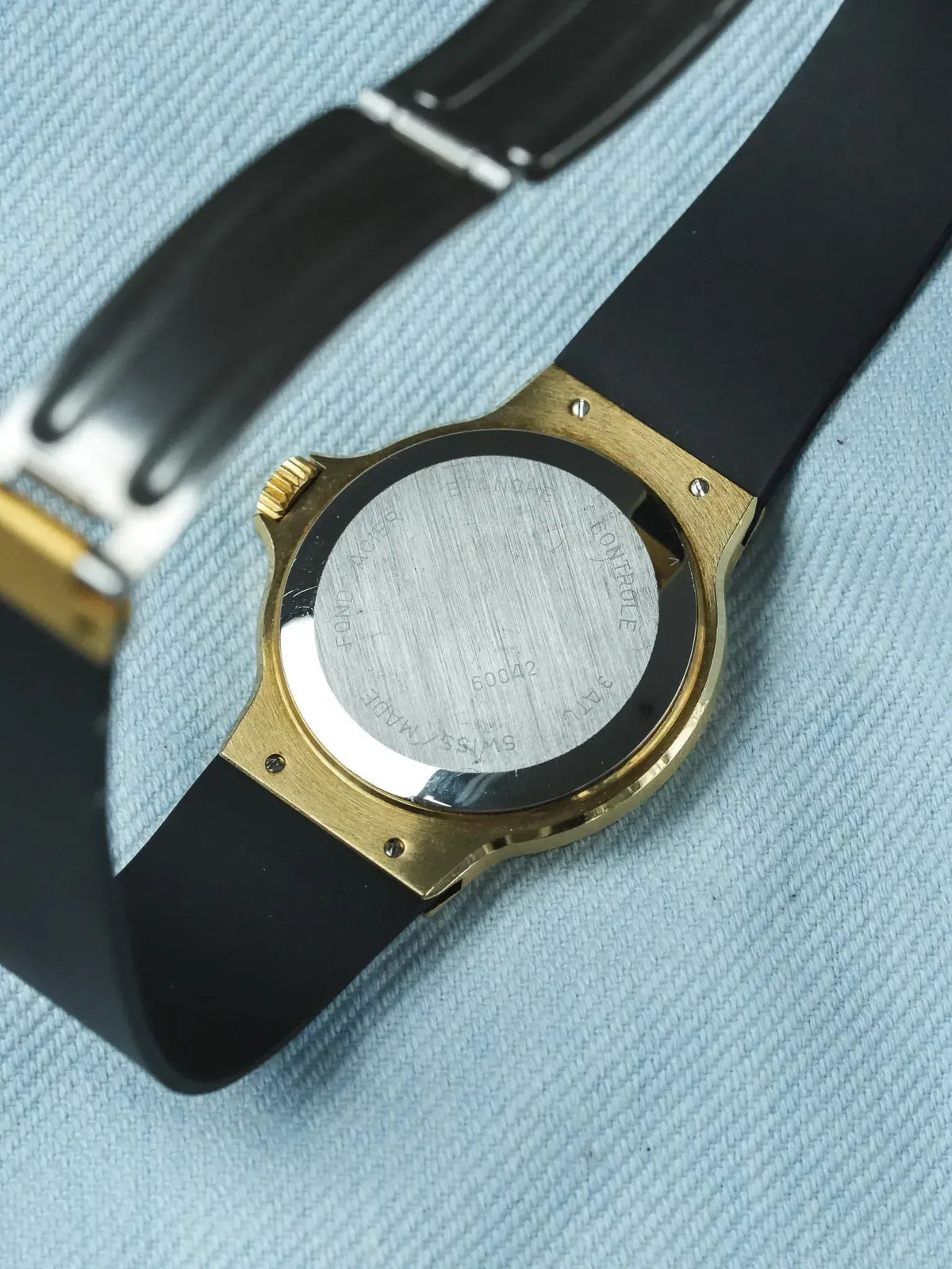 Vintage Hublot watch with gold case, black strap, and engraved stainless steel back