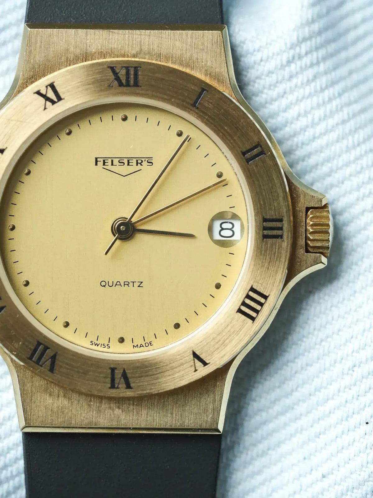 Felser's vintage quartz watch with gold case, cream dial, Roman numerals, and black strap