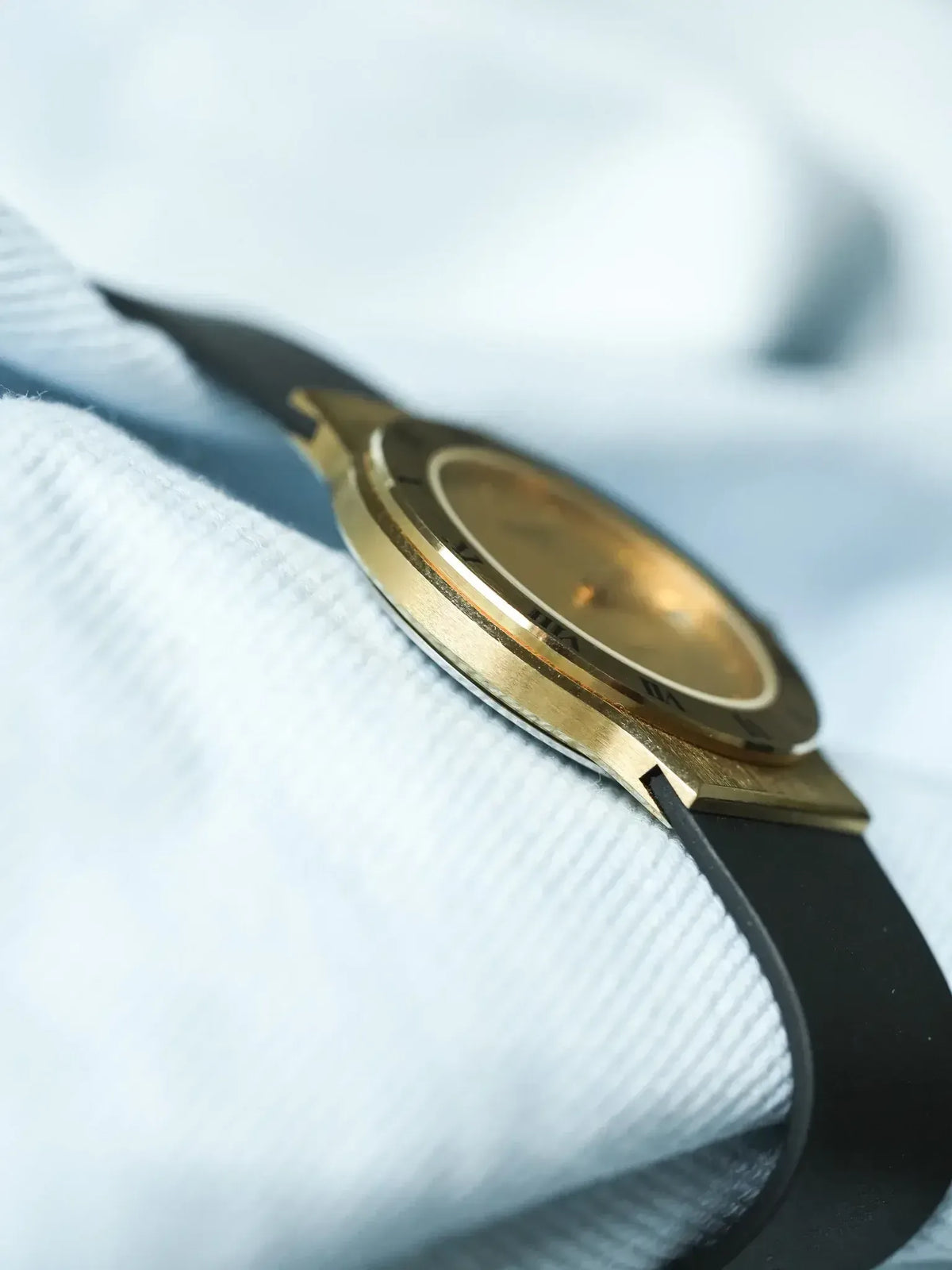 Vintage Cartier watch with gold case, black strap, worn on white fabric