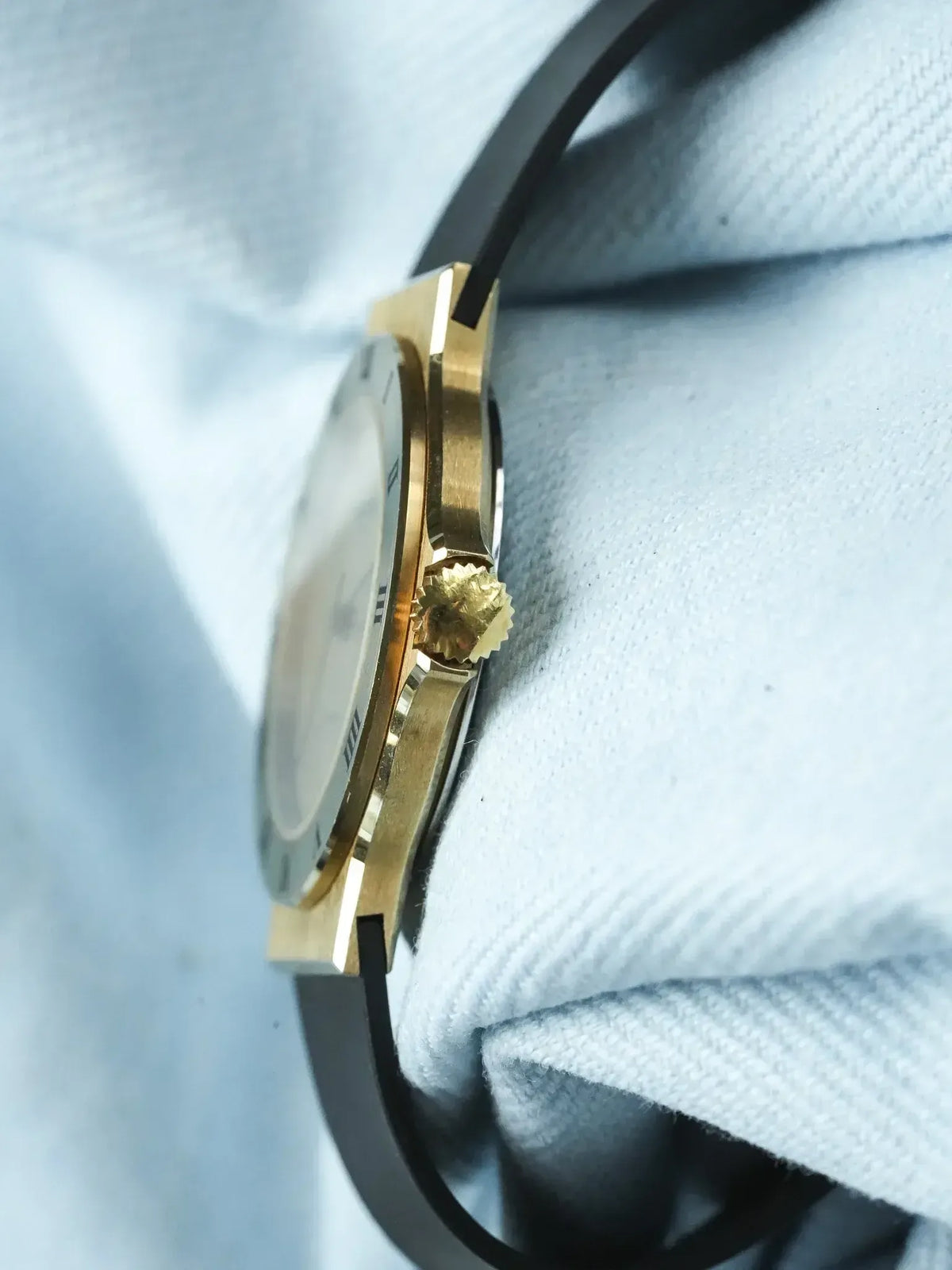 Vintage Cartier watch with gold case, white dial, black strap on fabric