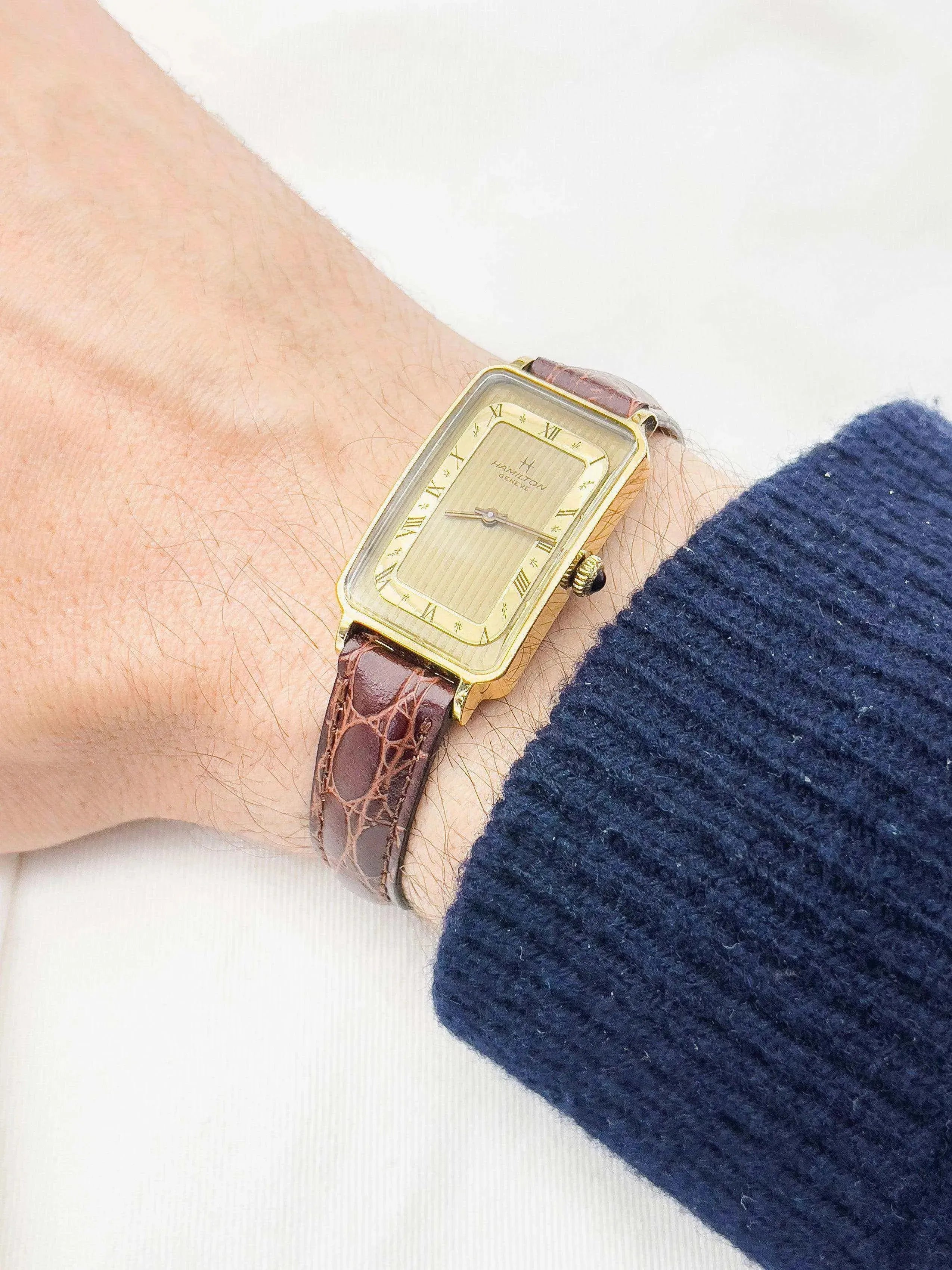 Hamilton Geneve vintage watch with gold case, cream dial, Roman numerals, brown alligator strap on wrist