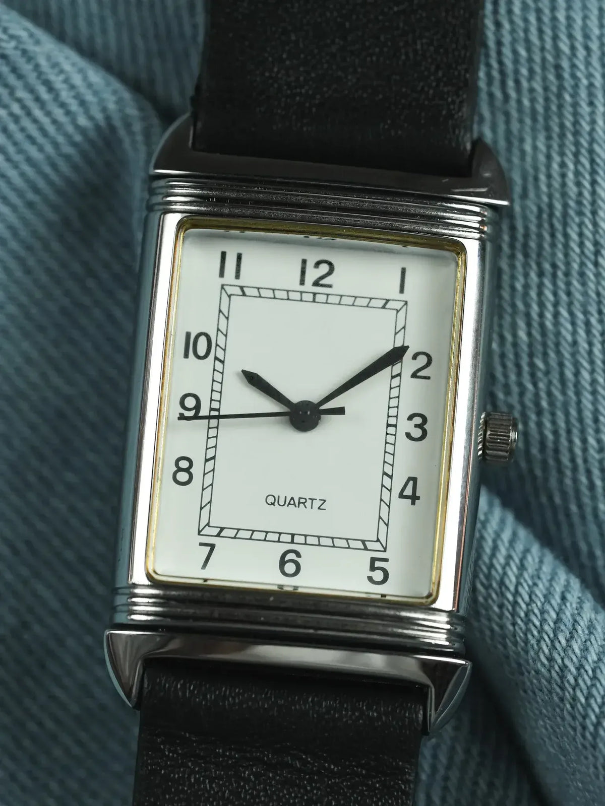 Vintage quartz watch with rectangular silver case, white dial, black leather strap