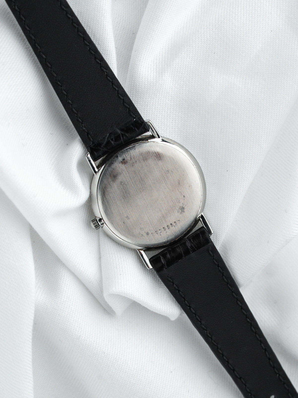 Dos d'une montre vintage en acier avec un bracelet en cuir noir