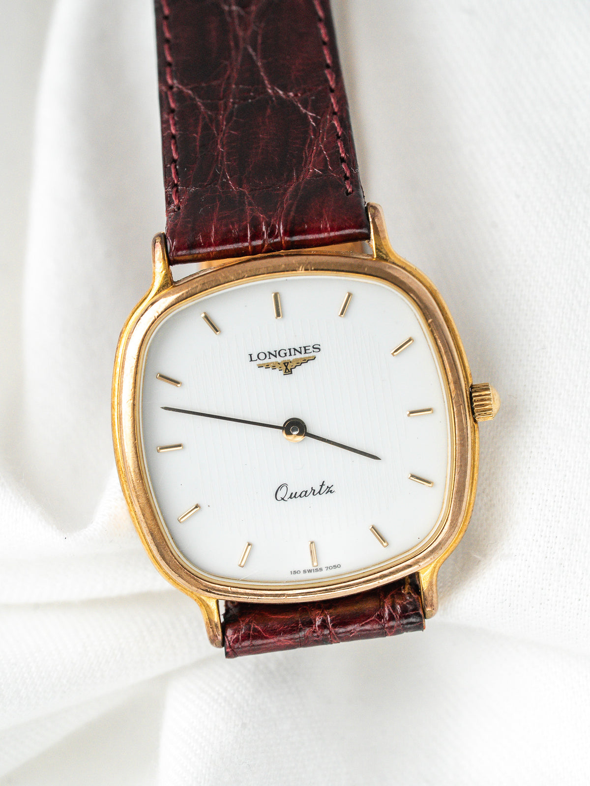 Montre Longines vintage Quartz, boîtier rectangulaire doré, cadran blanc et bracelet cuir bordeaux