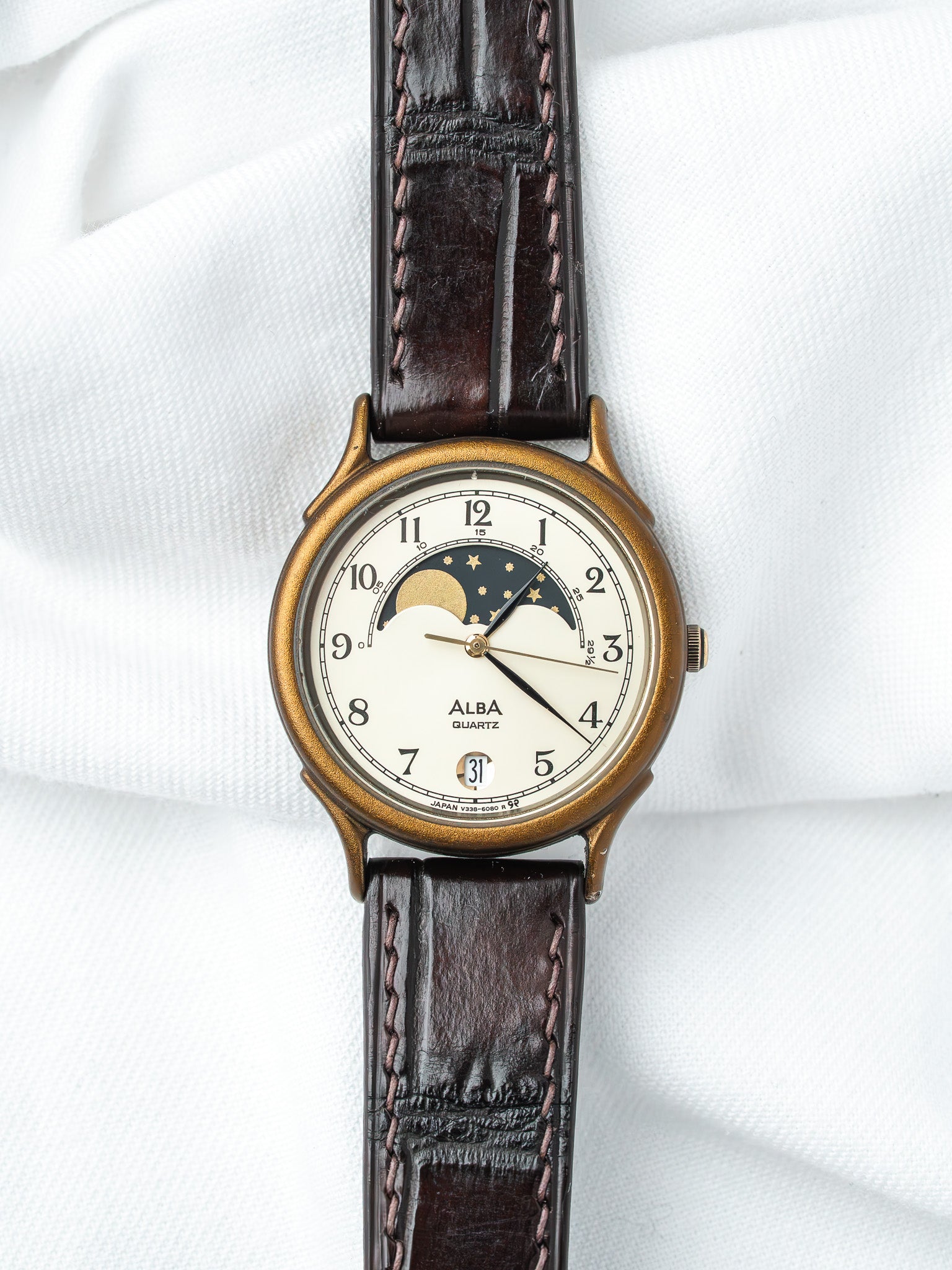 Alba Quartz vintage watch with moon phase, gold-tone case, brown leather strap on white fabric