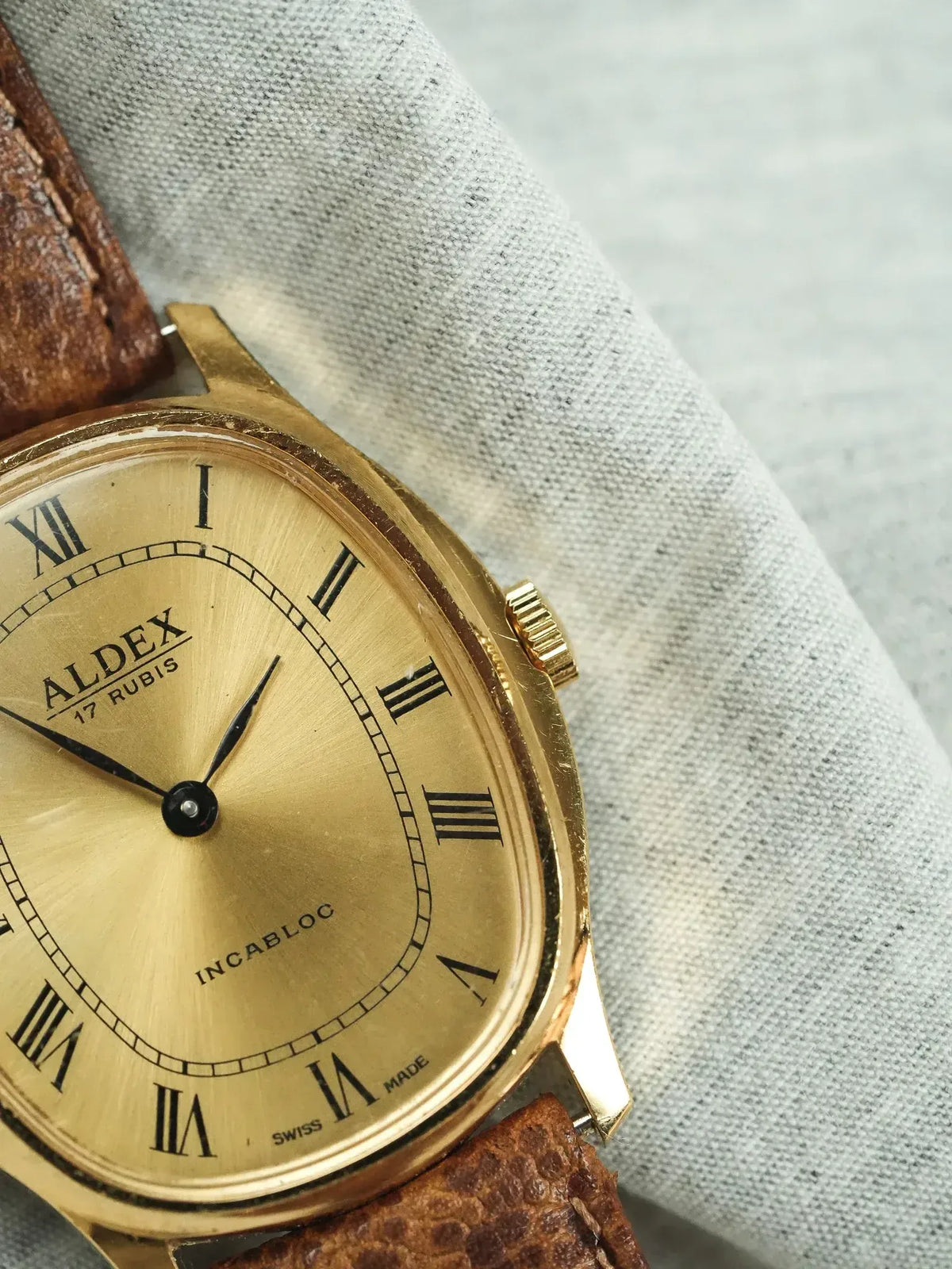 Aldex vintage watch with gold case, Roman numerals, and brown leather strap