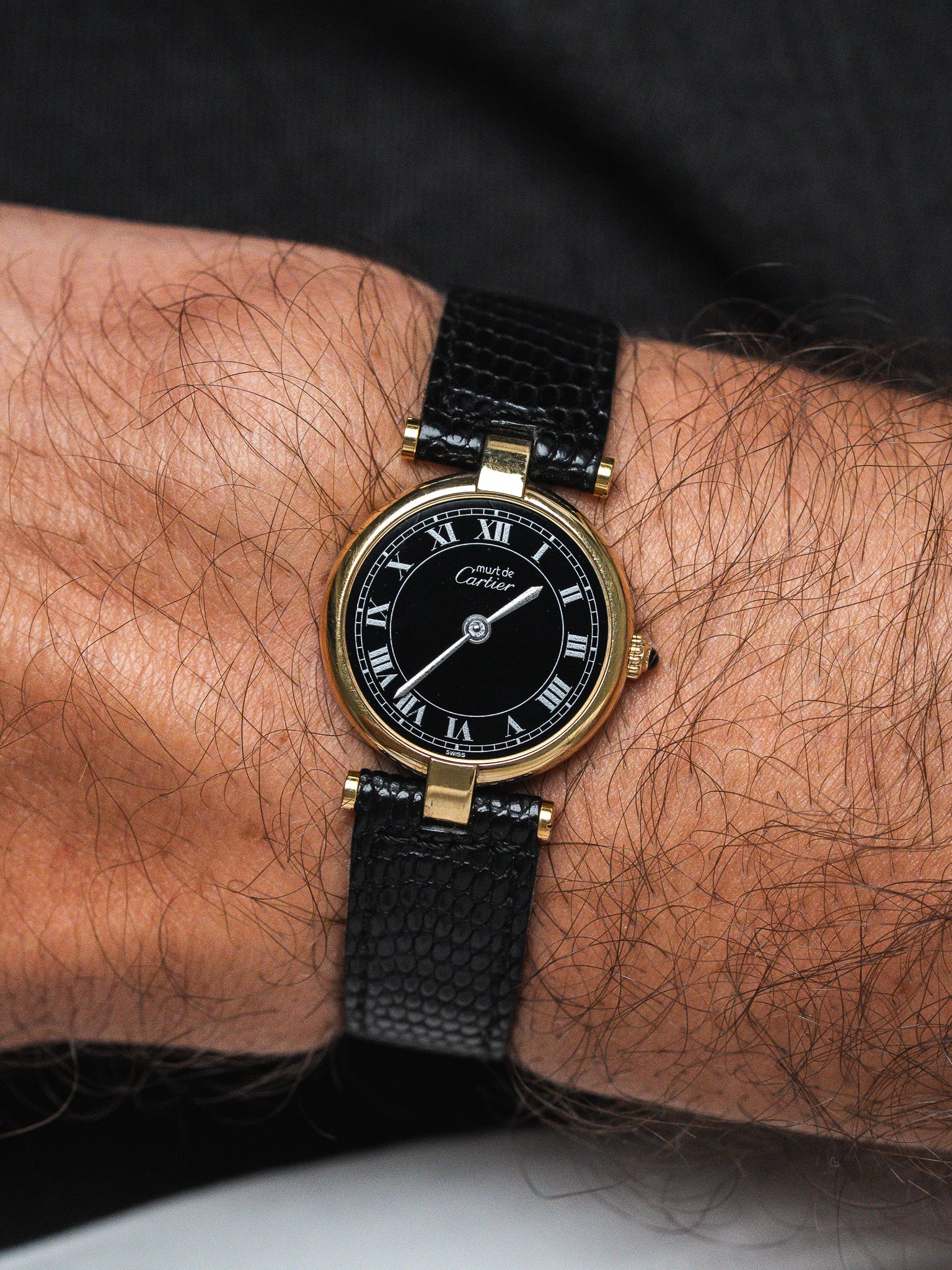 Cartier Must de Cartier vintage watch with black dial, gold case, and black leather strap