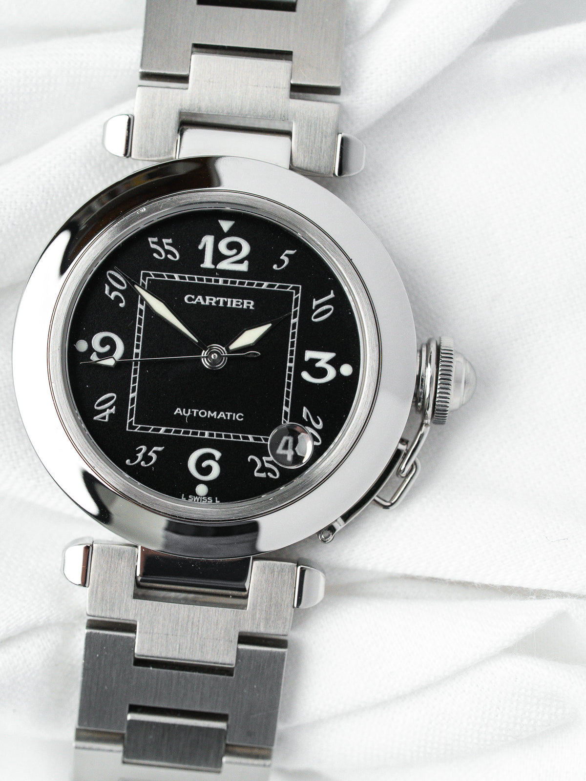 Cartier Pasha automatic watch with black dial, steel case and bracelet on white fabric