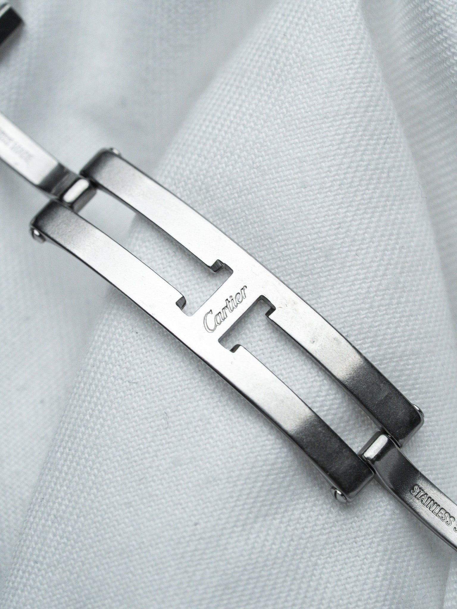 Cartier vintage watch clasp in stainless steel, engraved logo on white fabric