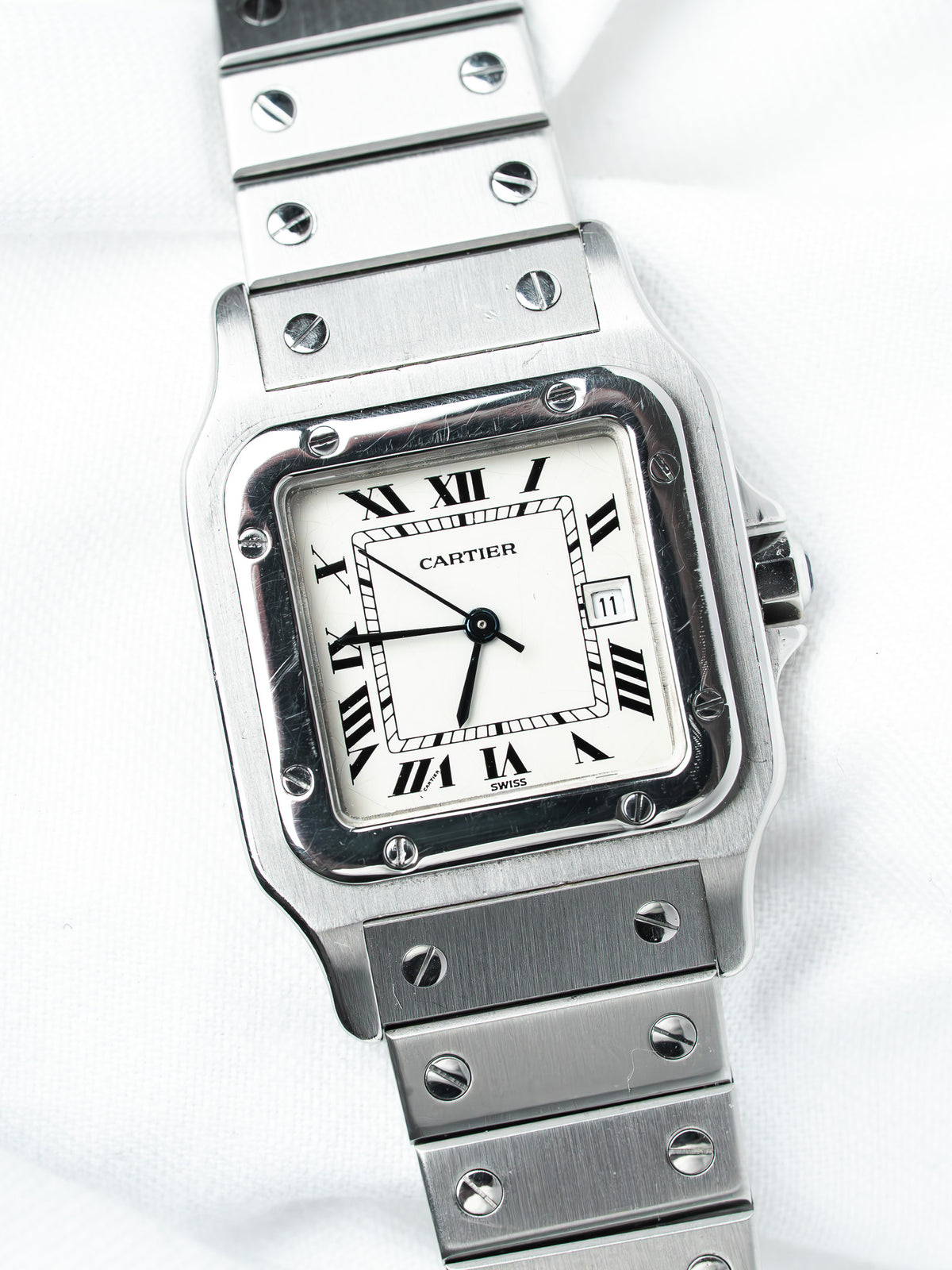 Cartier Santos watch with white dial, Roman numerals, and stainless steel bracelet