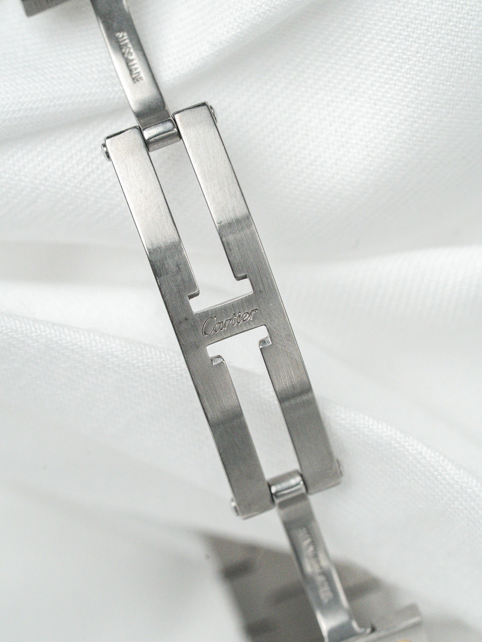 Cartier Santos watch clasp in brushed steel, engraved logo on white fabric