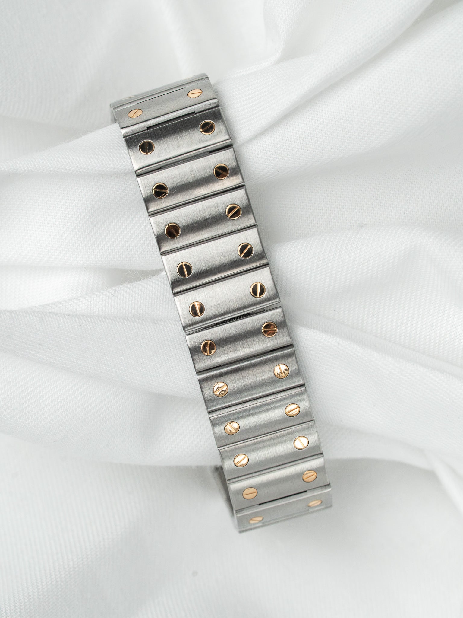 Cartier Santos bracelet in steel with gold screws, vintage design on white fabric