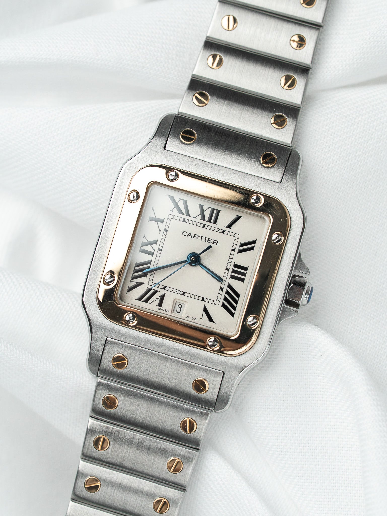 Cartier Santos watch with steel and gold case, white dial, Roman numerals, on white fabric