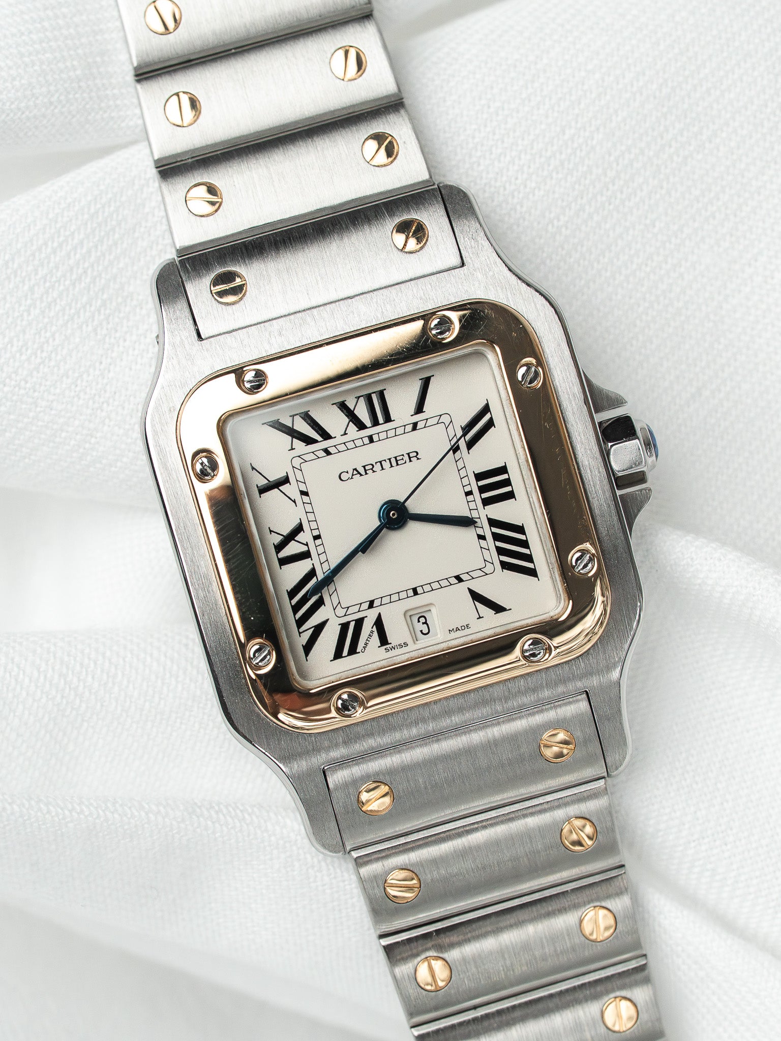 Cartier Santos watch with steel and gold case, white dial, Roman numerals, on white fabric