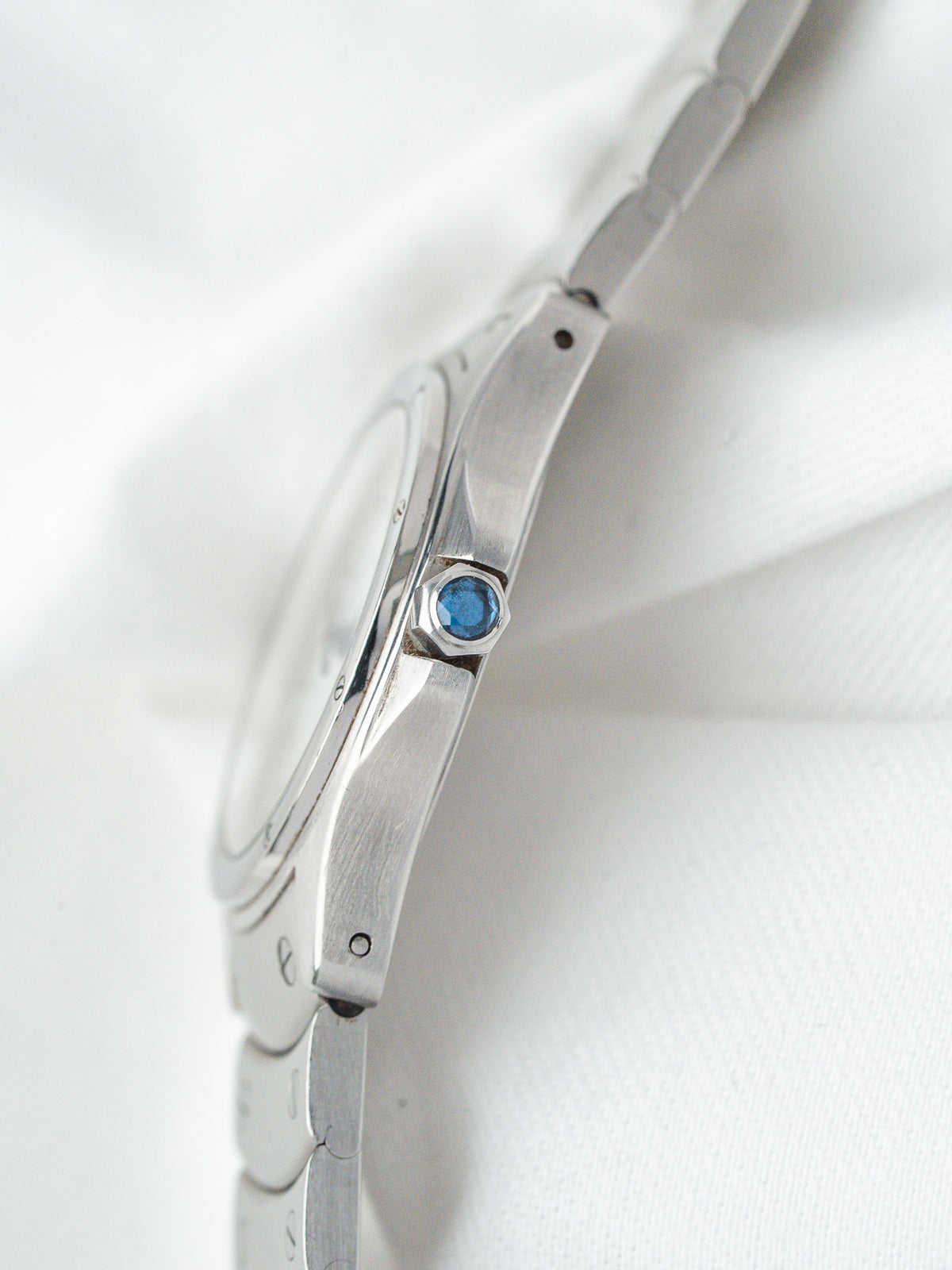 Cartier watch side view with blue sapphire crown, stainless steel case and bracelet