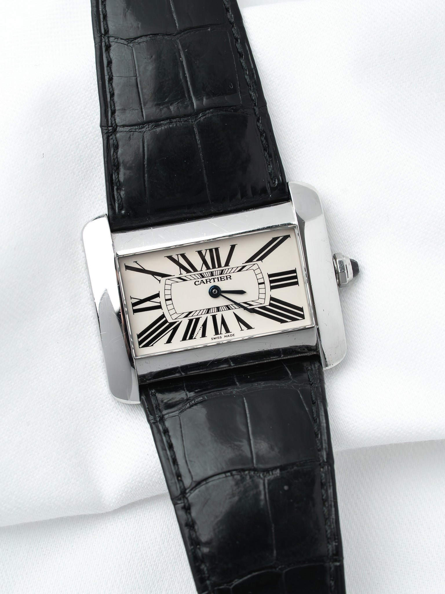 Cartier Tank watch with white dial, black Roman numerals, and black alligator strap on white background