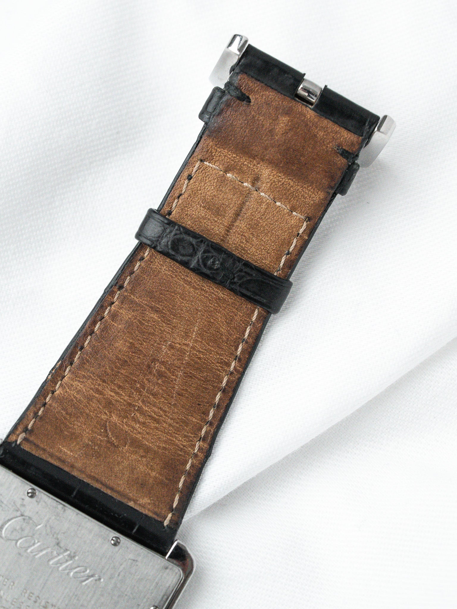 Cartier watch strap with brown leather and black alligator texture, silver hardware on white background