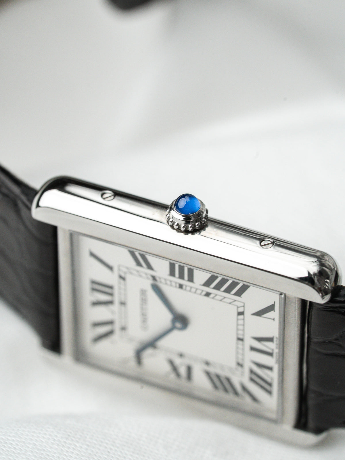 Montre Cartier Tank vintage, boîtier rectangulaire argenté, cadran blanc et bracelet cuir noir