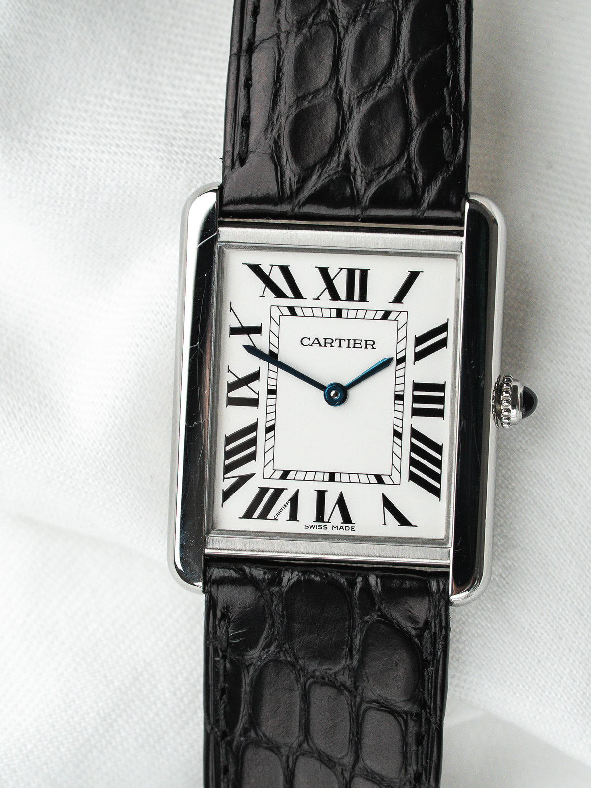Montre Cartier Tank vintage, boîtier rectangulaire argenté, cadran blanc et bracelet cuir noir