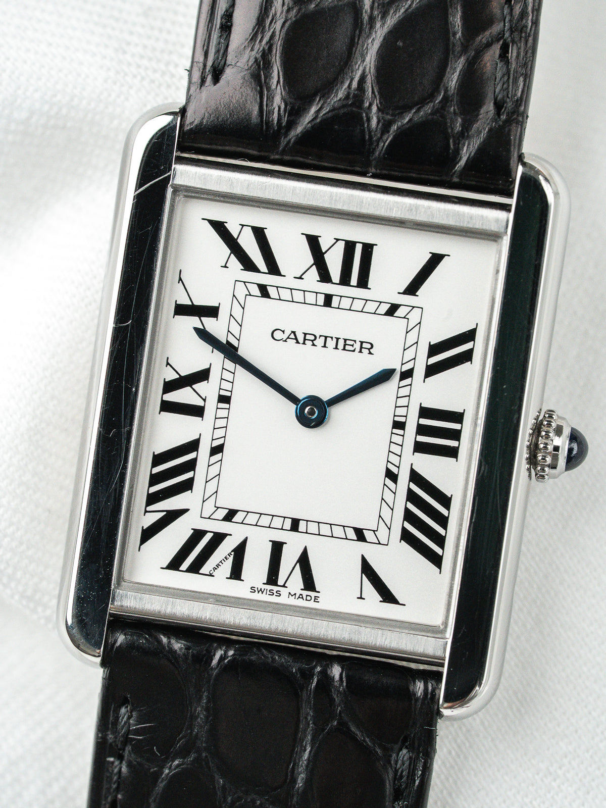 Montre Cartier Tank vintage, boîtier rectangulaire argenté, cadran blanc et bracelet cuir noir