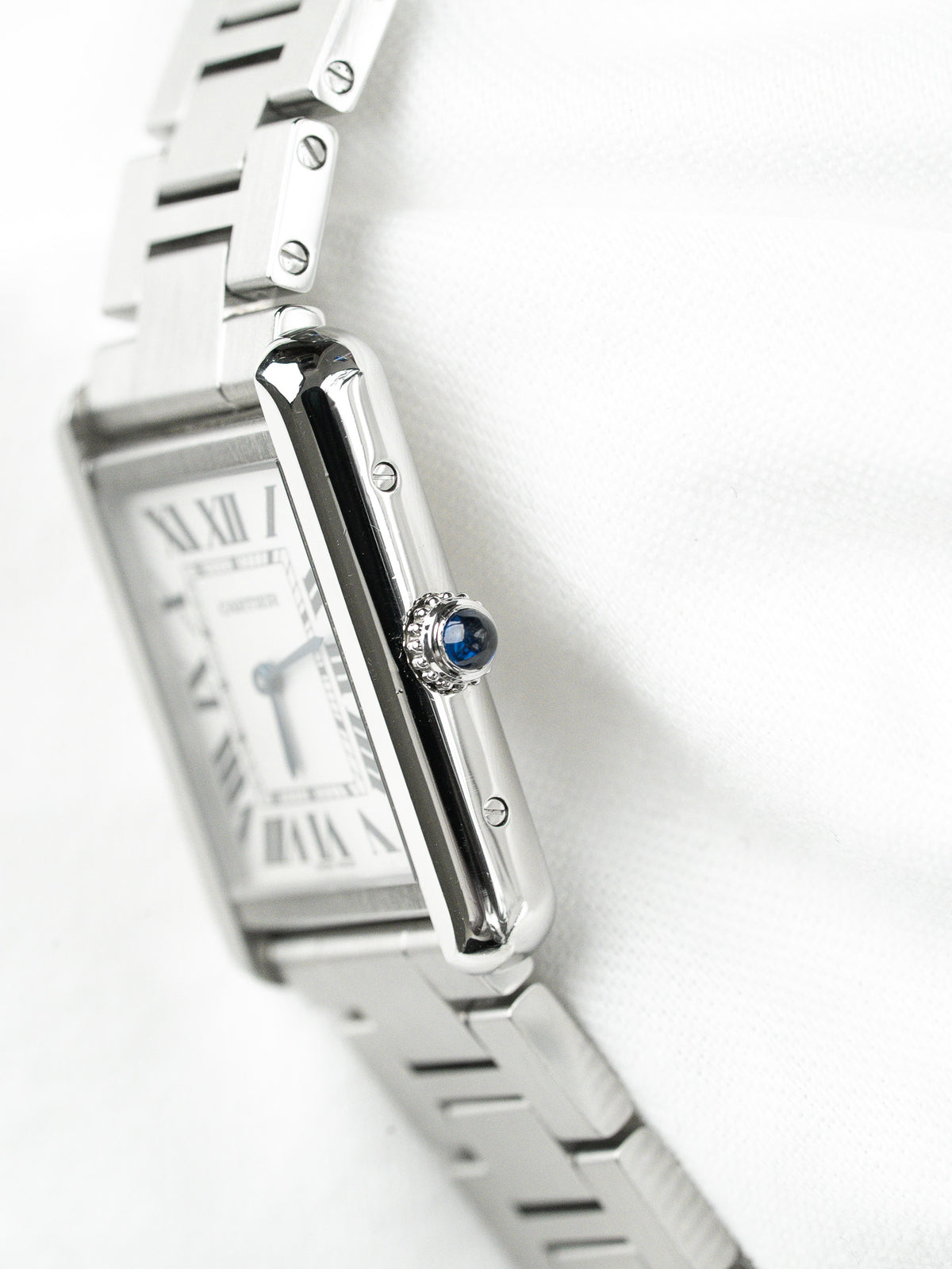 Montre Cartier vintage en acier, boîtier rectangulaire et couronne sertie d'un saphir bleu