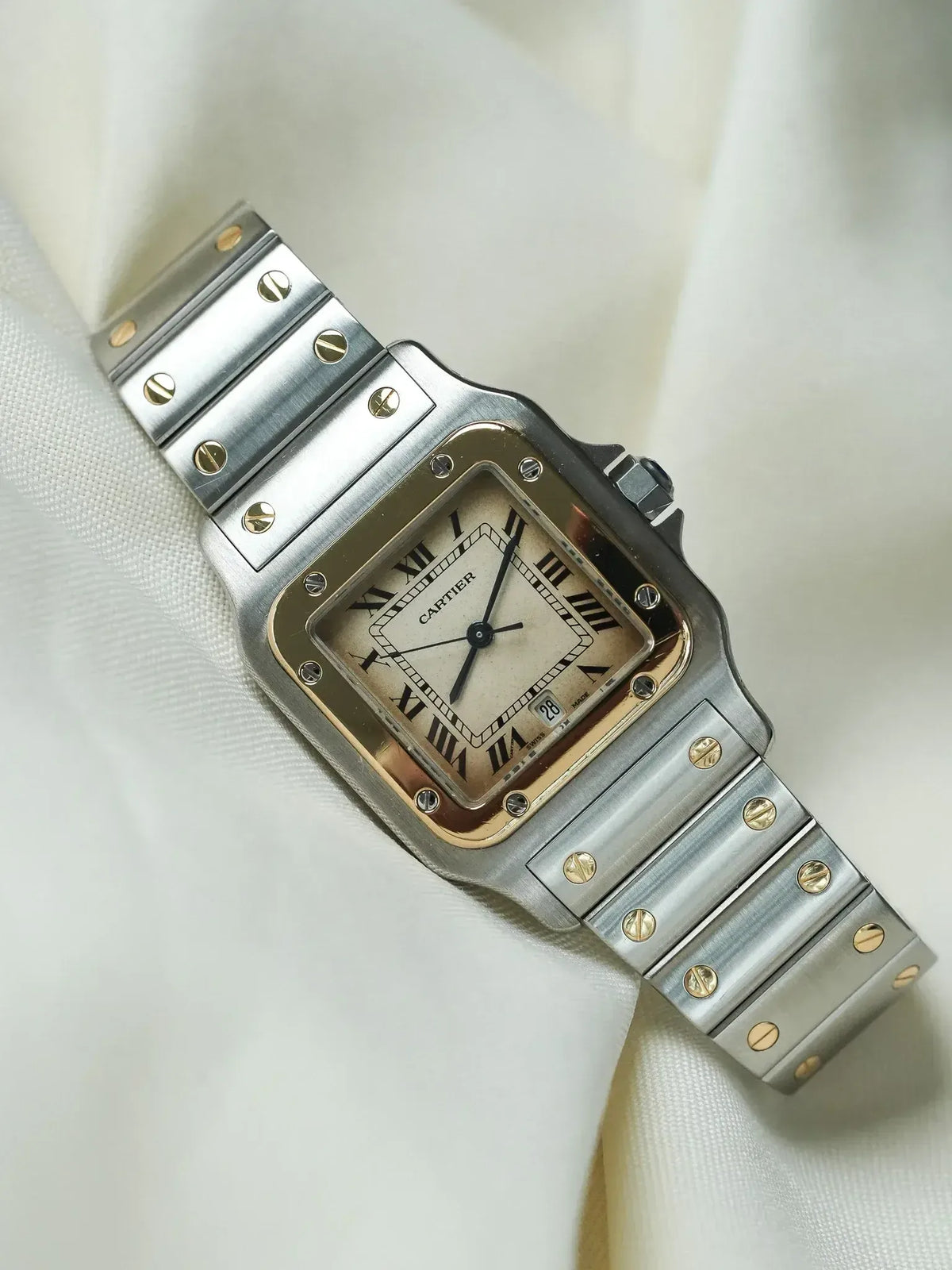 Cartier Santos watch with steel and gold case, cream dial, Roman numerals on white fabric