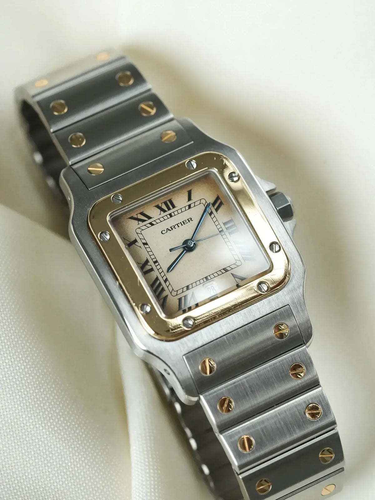Cartier Santos watch with square case, silver dial, Roman numerals, and two-tone bracelet