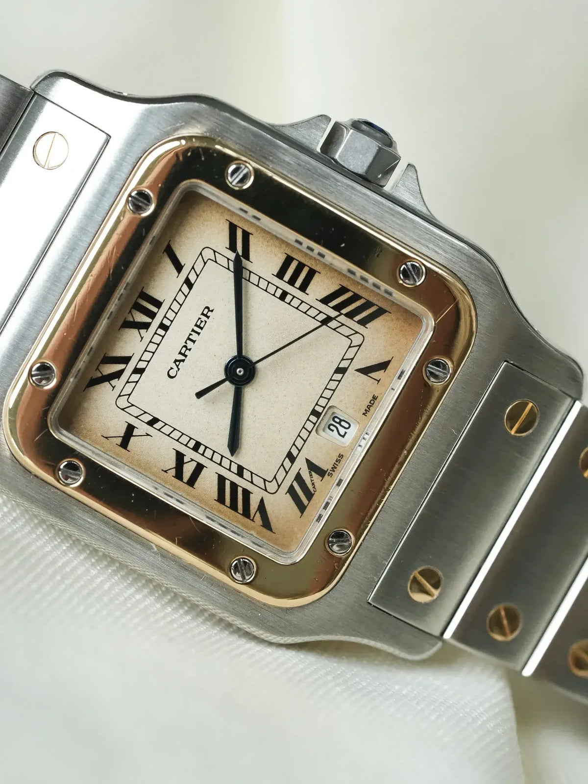 Cartier Santos watch with silver case, cream dial, Roman numerals, and date window
