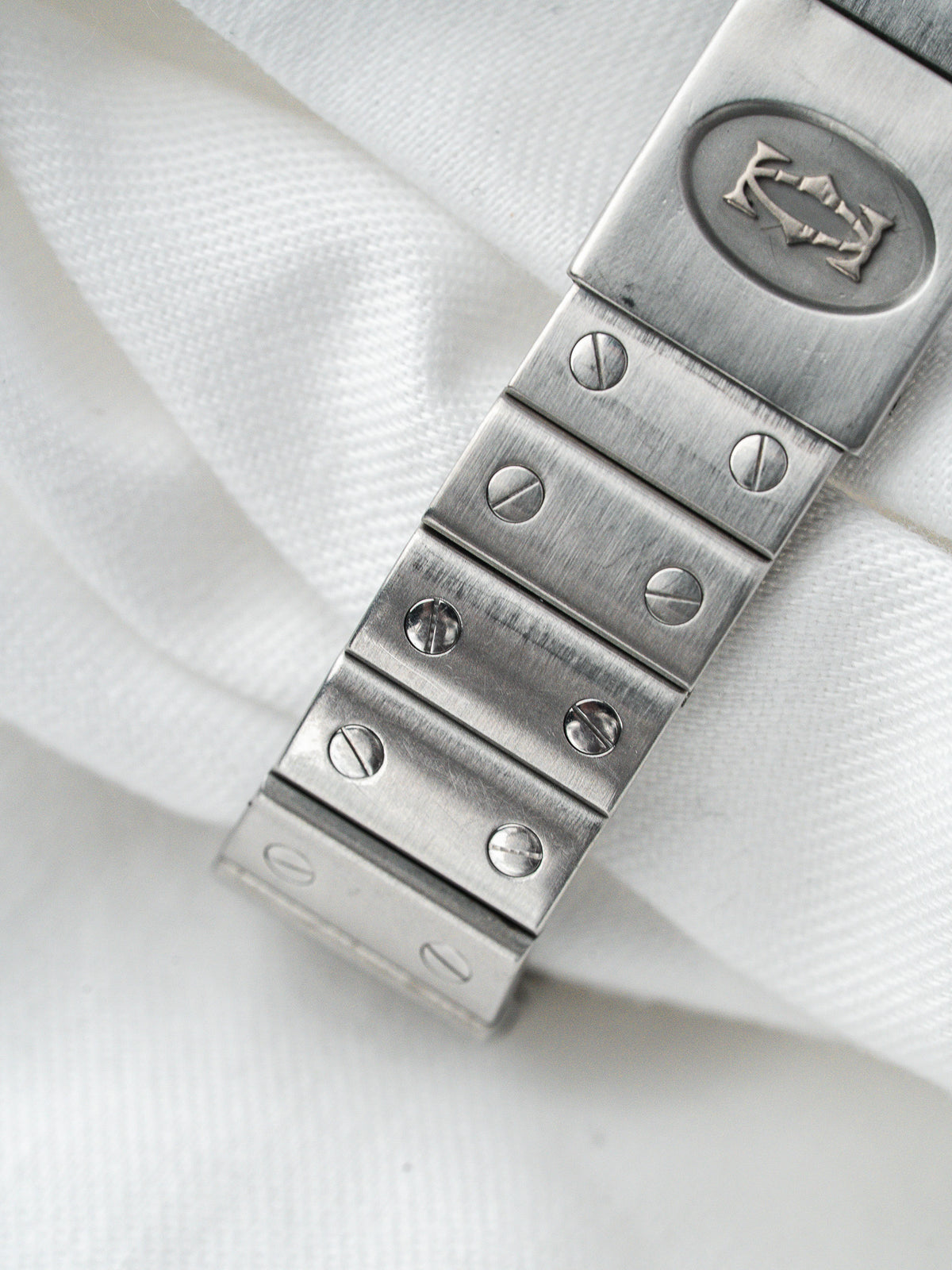 Bracelet de montre vintage en acier avec logo gravé sur fond de tissu blanc