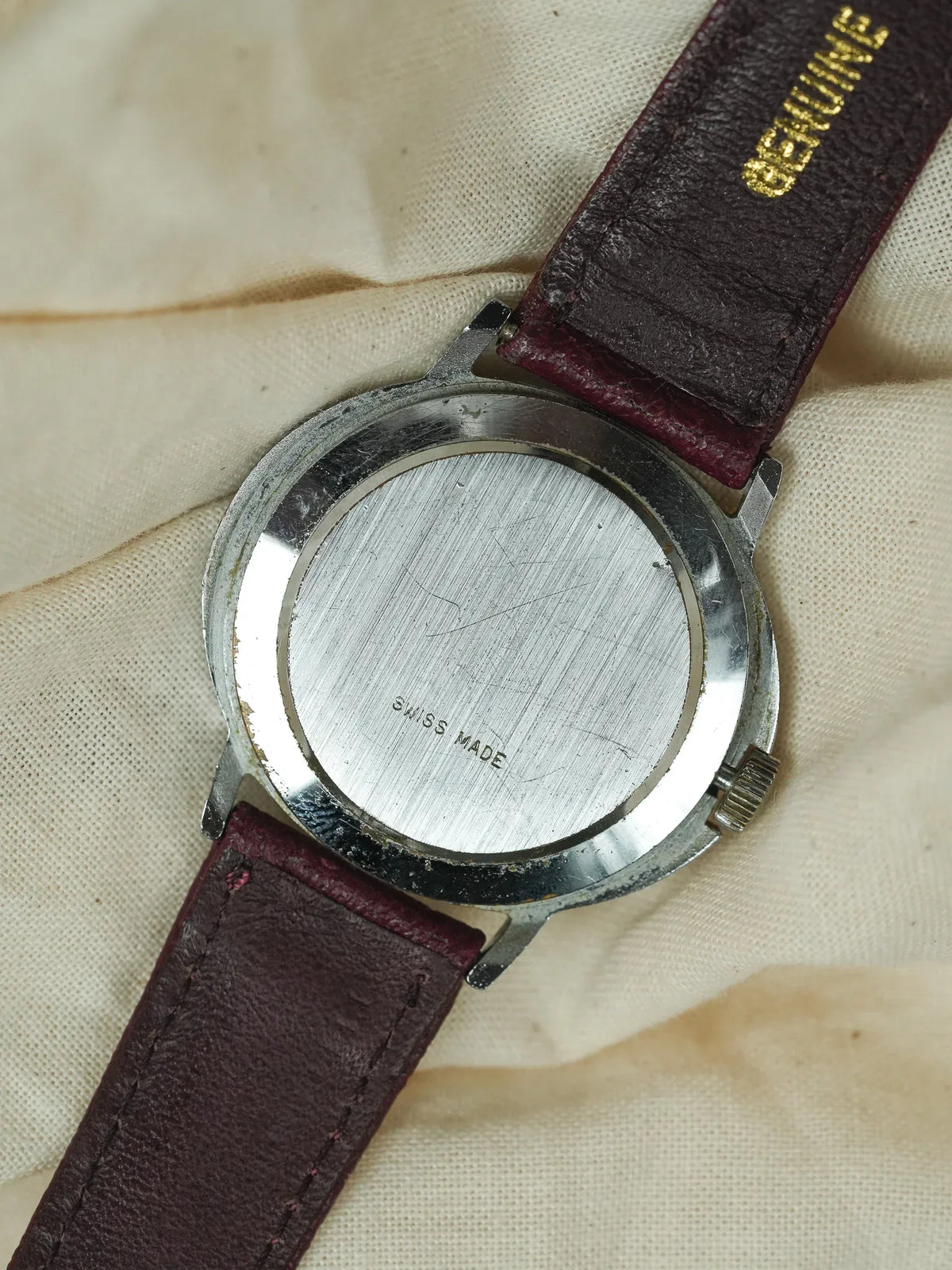 Vintage watch with stainless steel case back marked Swiss Made, burgundy leather strap
