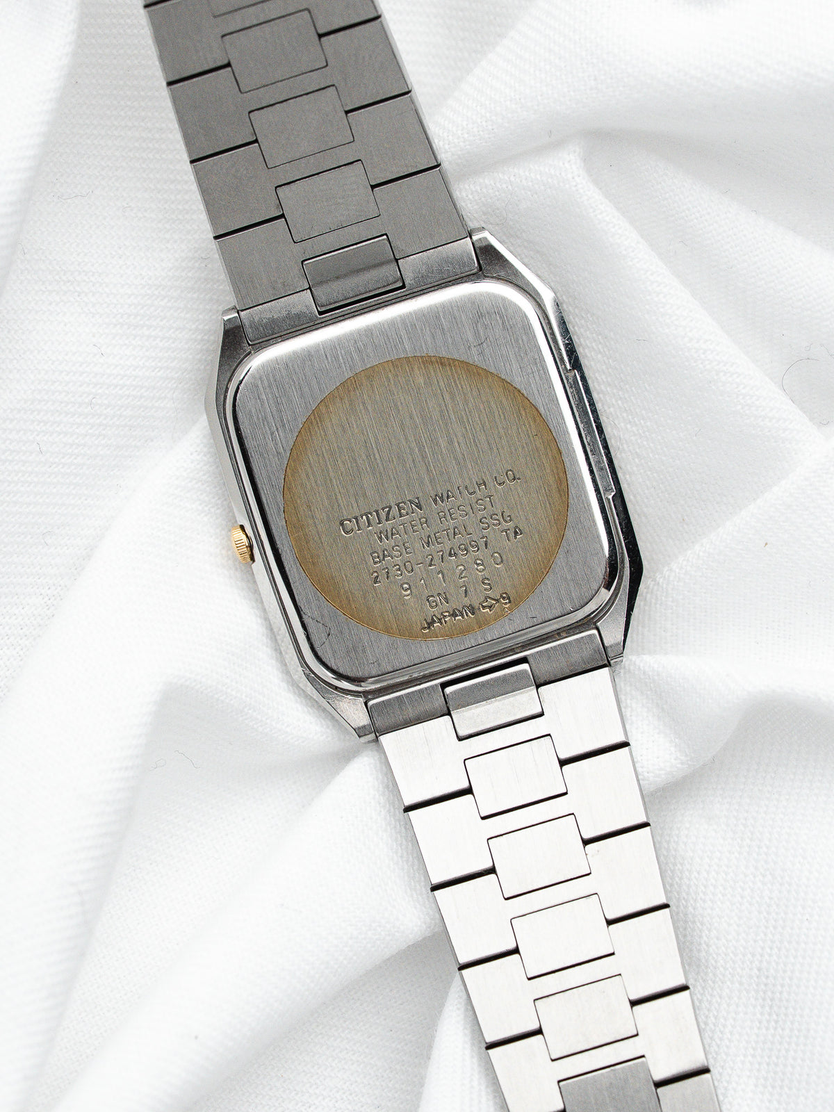 Dos en acier d'une montre Citizen vintage avec bracelet métallique sur fond blanc.