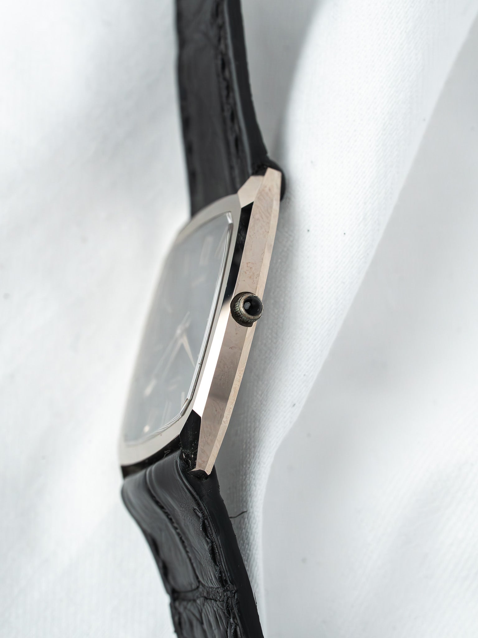 Vintage Cartier watch with rectangular case, black leather strap, on white fabric