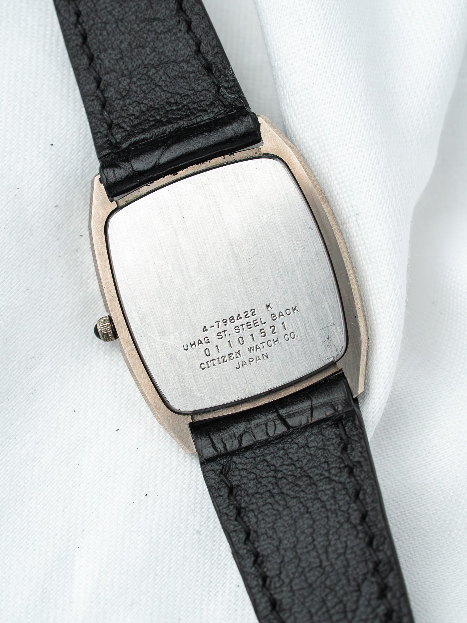 Citizen vintage watch with steel case back, black leather strap, displayed on white fabric