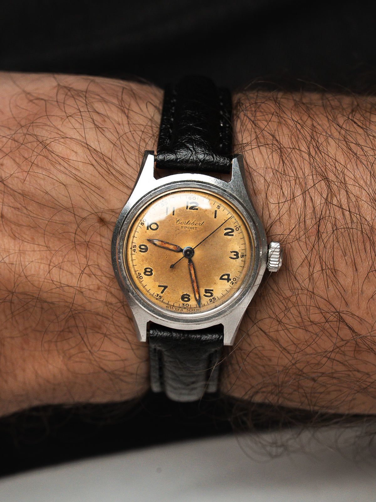 Montre vintage Certina Sport, cadran doré patiné et bracelet cuir noir, portée au poignet