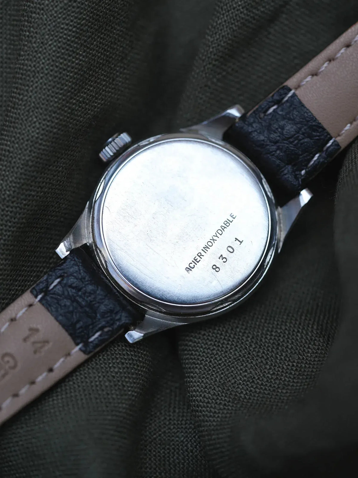 Vintage watch back with stainless steel case, engraved 'ACIER INOXYDABLE 8301', leather strap