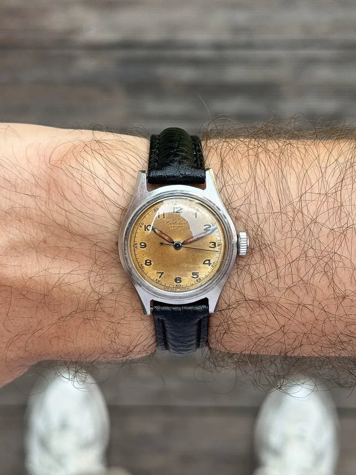 Vintage Cortebert Sport watch with cream dial, black leather strap, worn on wrist