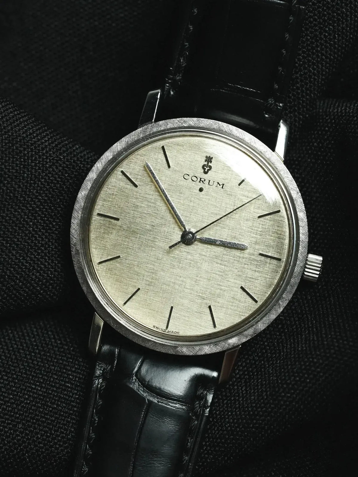 Vintage Corum watch with silvered dial, textured bezel, and black leather strap